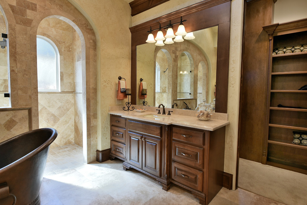 Inspiration for a large mediterranean master beige tile and ceramic tile travertine floor and beige floor bathroom remodel in Houston with raised-panel cabinets, medium tone wood cabinets, beige walls, an undermount sink and marble countertops