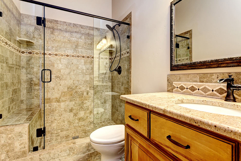 Bild på ett mellanstort medelhavsstil badrum med dusch, med luckor med upphöjd panel, skåp i ljust trä, beige kakel, granitbänkskiva, en dusch i en alkov, stenkakel, beige väggar, ett undermonterad handfat, beiget golv och dusch med gångjärnsdörr