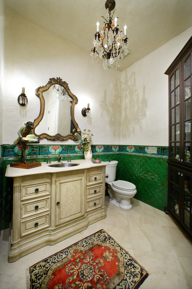 Idéer för mellanstora medelhavsstil badrum med dusch, med luckor med upphöjd panel, beige skåp, beige kakel, vit kakel, blå kakel, grön kakel, gröna väggar, en toalettstol med separat cisternkåpa, glaskakel, kalkstensgolv, ett undermonterad handfat och granitbänkskiva