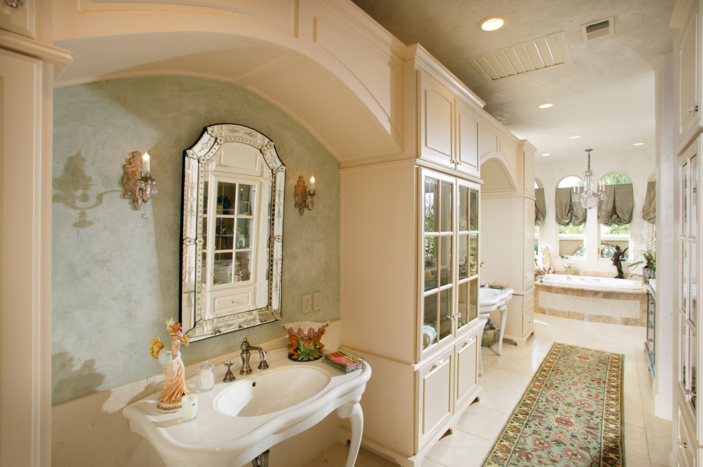 Expansive traditional ensuite bathroom in Sacramento with raised-panel cabinets, a built-in bath, green walls, a console sink, beige cabinets, an alcove shower, beige tiles, white tiles, stone tiles and ceramic flooring.