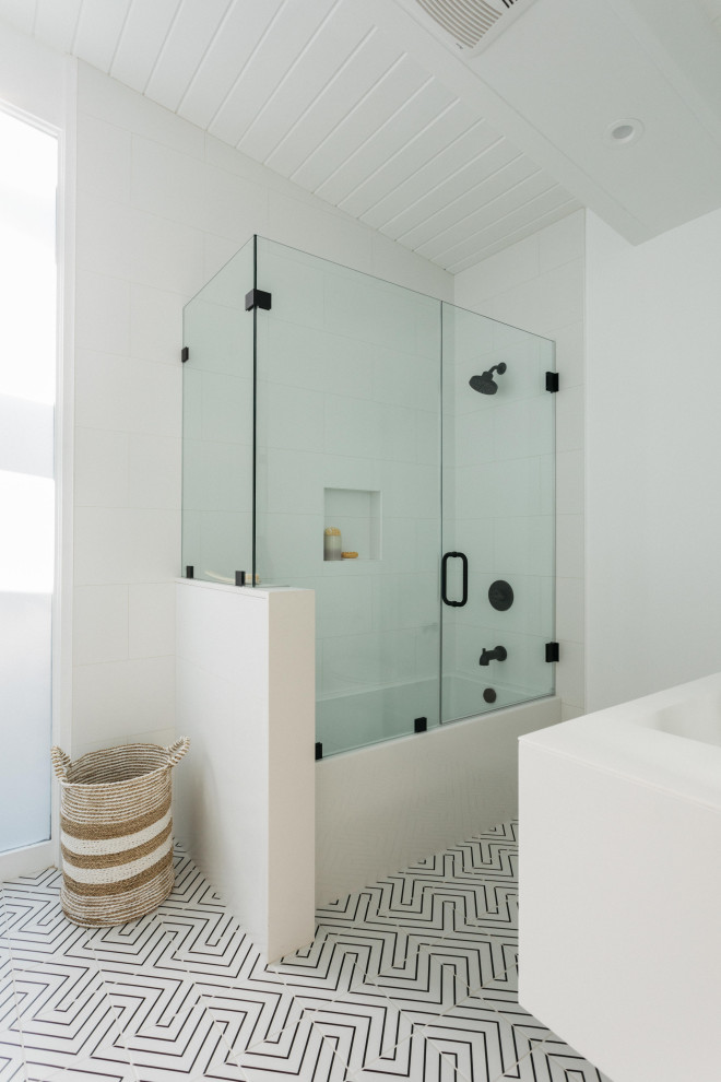 Cette photo montre une salle de bain tendance avec une baignoire en alcôve, un combiné douche/baignoire, un carrelage blanc, un mur blanc, carreaux de ciment au sol, un sol multicolore, une cabine de douche à porte battante, un plafond en lambris de bois et du carrelage bicolore.