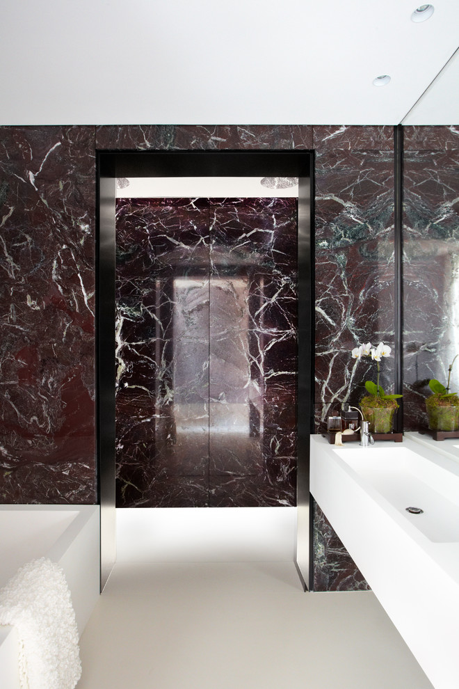 Foto di una stanza da bagno design con lavabo integrato, vasca ad alcova e piastrelle di marmo