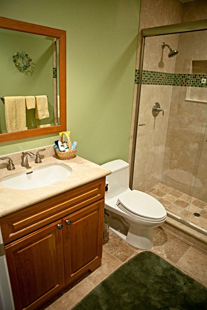 Small classic family bathroom in Orange County with a submerged sink, raised-panel cabinets, medium wood cabinets, solid surface worktops, a corner shower, a two-piece toilet, beige tiles, porcelain tiles, green walls and porcelain flooring.