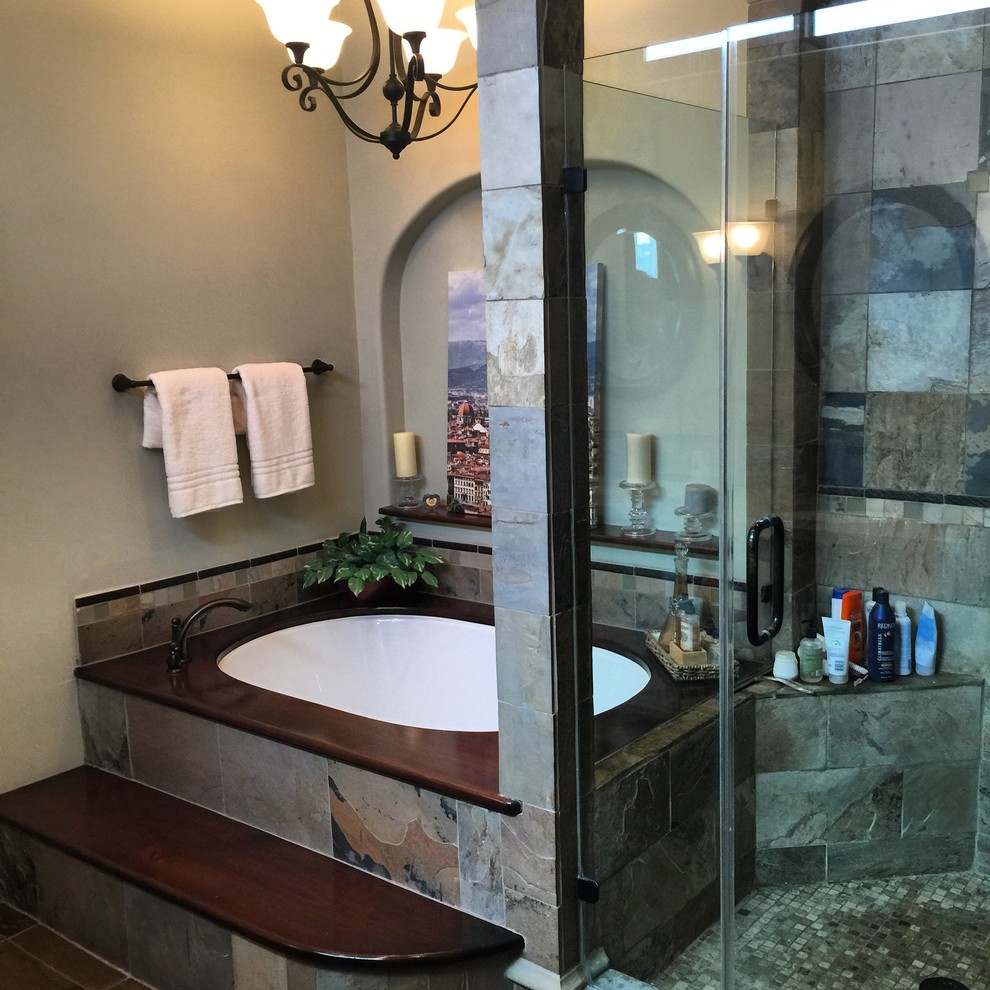 Cette photo montre une grande salle de bain principale moderne en bois foncé avec un placard à porte plane, une baignoire encastrée, une douche d'angle, un carrelage multicolore, un carrelage de pierre, un mur beige, un sol en vinyl, un lavabo encastré et un plan de toilette en bois.