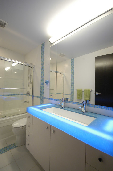 На фото: ванная комната среднего размера в современном стиле с плоскими фасадами, белыми фасадами, ванной в нише, душем над ванной, синей плиткой, белой плиткой, плиткой мозаикой, белыми стенами, полом из керамической плитки, душевой кабиной, раковиной с несколькими смесителями, столешницей из оникса и синей столешницей