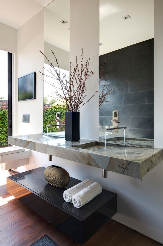 Aménagement d'une salle de bain contemporaine avec un lavabo intégré, WC suspendus et un carrelage noir.