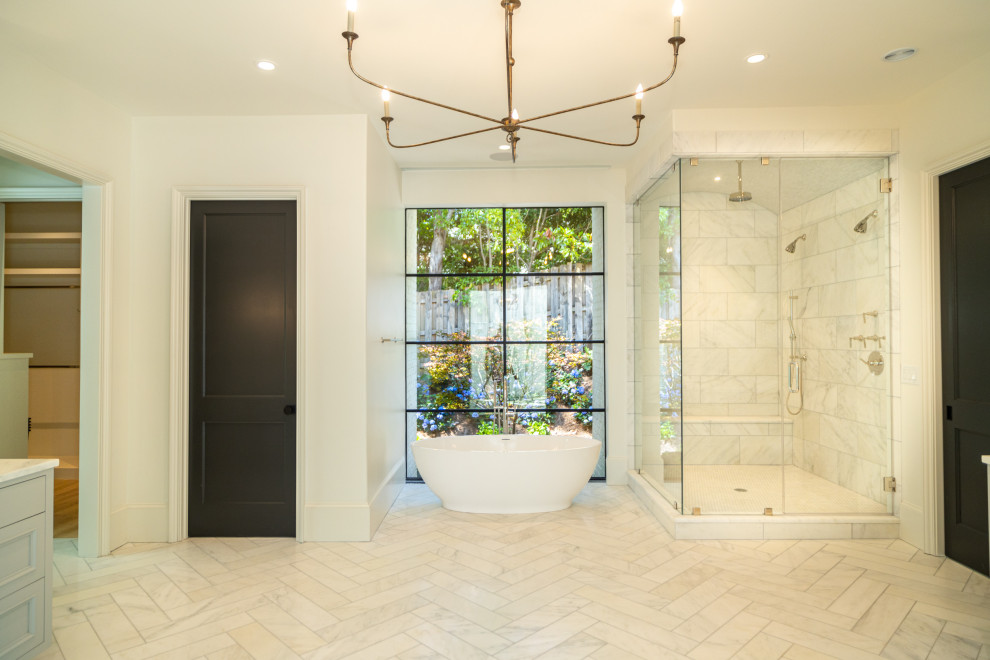 This is an example of a large modern ensuite bathroom in Atlanta with recessed-panel cabinets, grey cabinets, a freestanding bath, a corner shower, a one-piece toilet, white tiles, marble tiles, white walls, light hardwood flooring, a submerged sink, marble worktops, white floors, an open shower, white worktops, a shower bench, a single sink and a built in vanity unit.