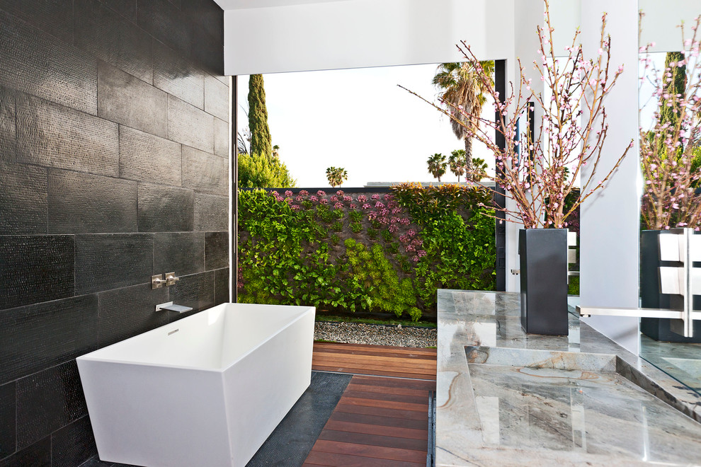 Modelo de cuarto de baño principal contemporáneo con bañera exenta, baldosas y/o azulejos negros y lavabo integrado