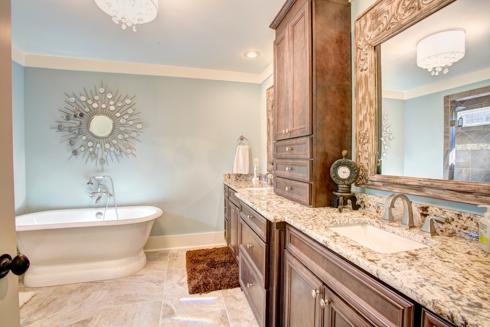 На фото: ванная комната среднего размера в классическом стиле с врезной раковиной, отдельно стоящей ванной, душем в нише, фасадами с выступающей филенкой, коричневыми фасадами, столешницей из гранита, керамической плиткой, синими стенами и полом из керамической плитки