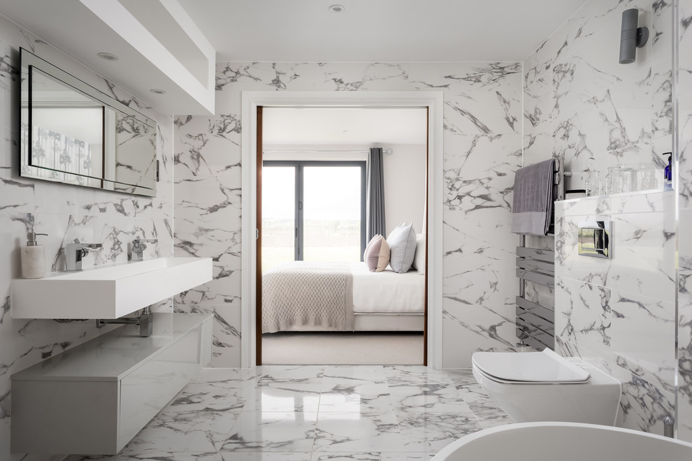 Idées déco pour une grande salle de bain principale contemporaine avec WC à poser, un carrelage noir et blanc, un mur multicolore, un sol en marbre, un lavabo suspendu, un sol multicolore et un plan de toilette blanc.