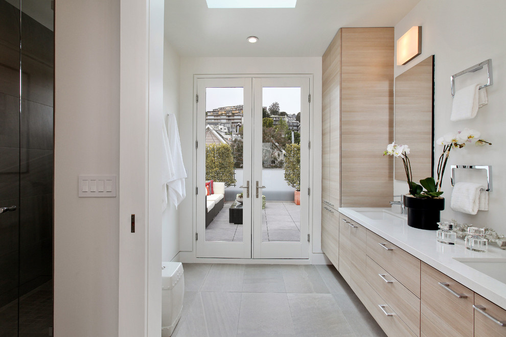 Diseño de cuarto de baño contemporáneo con armarios con paneles lisos, puertas de armario de madera clara, paredes blancas y lavabo bajoencimera