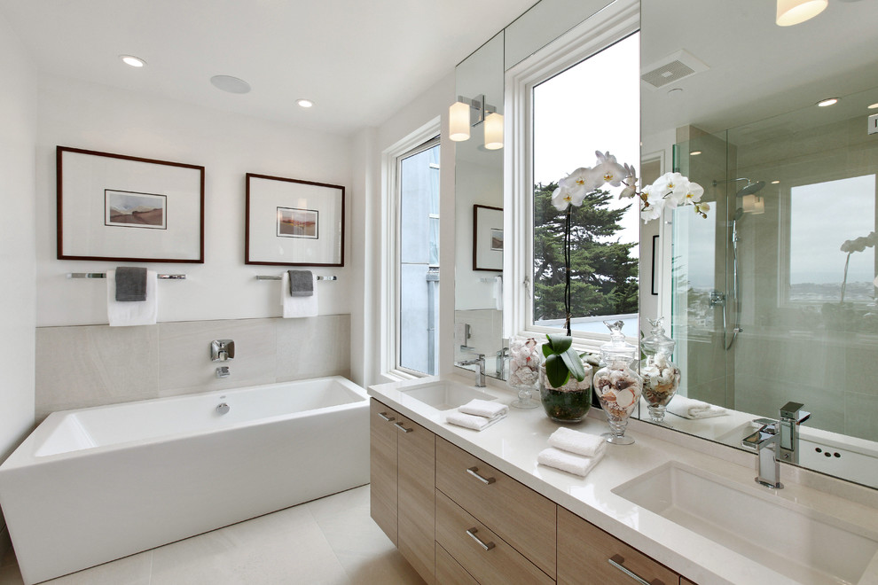 Contemporary bathroom in San Francisco with flat-panel cabinets, light wood cabinets, a freestanding bath, grey tiles, white walls and a submerged sink.