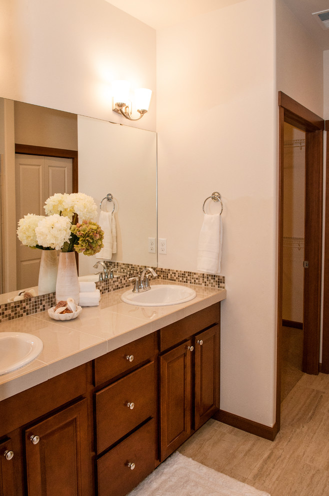 Réalisation d'une salle de bain design en bois brun avec un lavabo posé, un placard avec porte à panneau encastré, un plan de toilette en carrelage, un mur blanc et parquet clair.