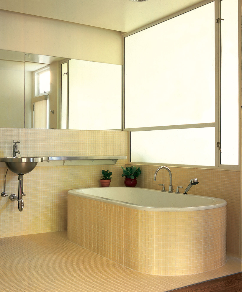 Inspiration för ett industriellt badrum, med ett fristående badkar, mosaik, bänkskiva i rostfritt stål och ett väggmonterat handfat