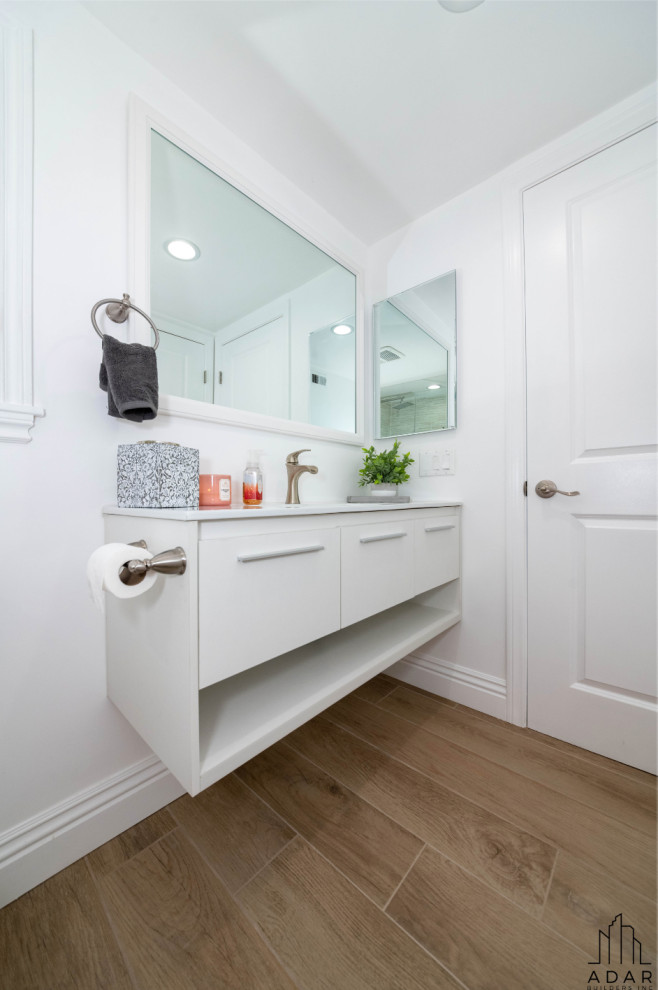 Modern family bathroom in Los Angeles with white cabinets, stone tiles, medium hardwood flooring, marble worktops, white worktops and a single sink.