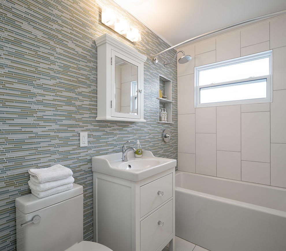 Inredning av ett klassiskt mellanstort en-suite badrum, med släta luckor, vita skåp, bänkskiva i akrylsten, en dusch/badkar-kombination, flerfärgad kakel, glaskakel och klinkergolv i keramik