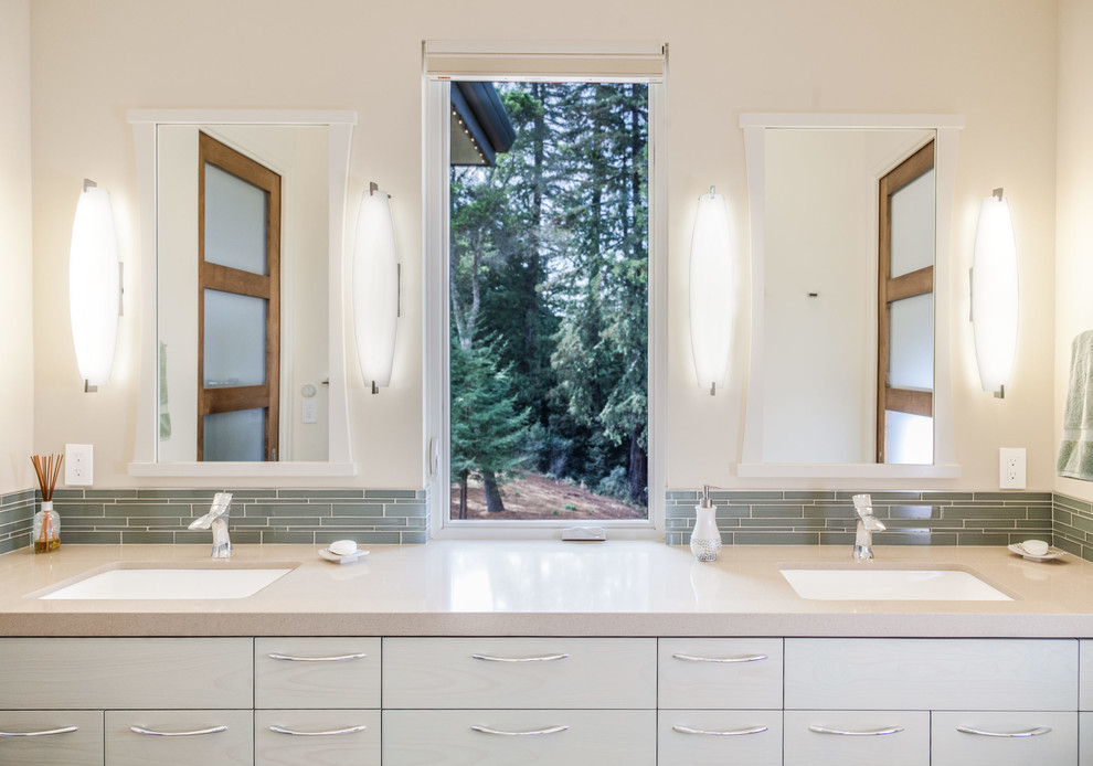 Immagine di una stanza da bagno per bambini minimalista con ante lisce, WC sospeso, piastrelle beige, lastra di vetro, pareti beige, pavimento in gres porcellanato e lavabo sottopiano
