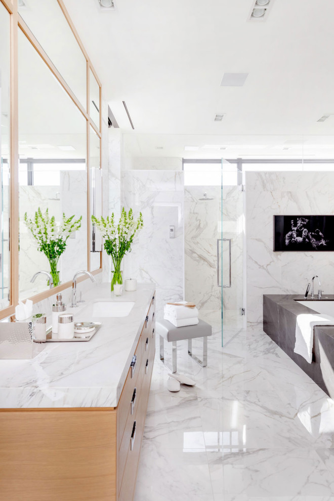 Стильный дизайн: огромная главная ванная комната в современном стиле с плоскими фасадами, светлыми деревянными фасадами, полновстраиваемой ванной, душем в нише, серой плиткой, белой плиткой, керамогранитной плиткой, врезной раковиной, разноцветным полом, душем с распашными дверями, белой столешницей, тумбой под одну раковину и подвесной тумбой - последний тренд