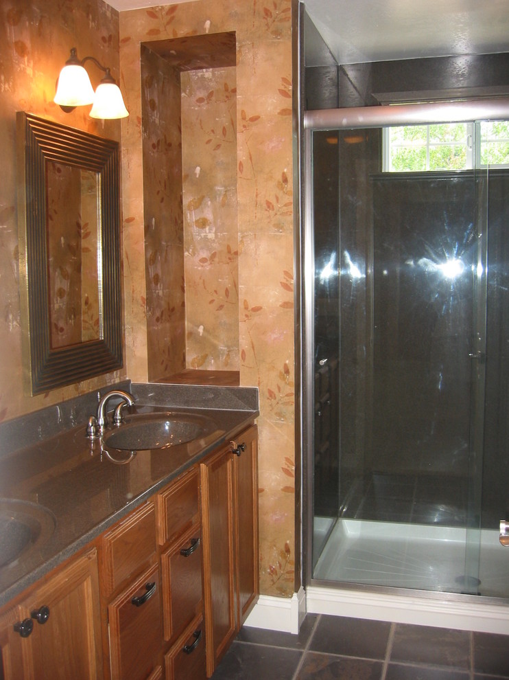 Alcove shower - mid-sized craftsman master brown tile linoleum floor alcove shower idea in Denver with an integrated sink, recessed-panel cabinets, medium tone wood cabinets, solid surface countertops, a one-piece toilet and orange walls