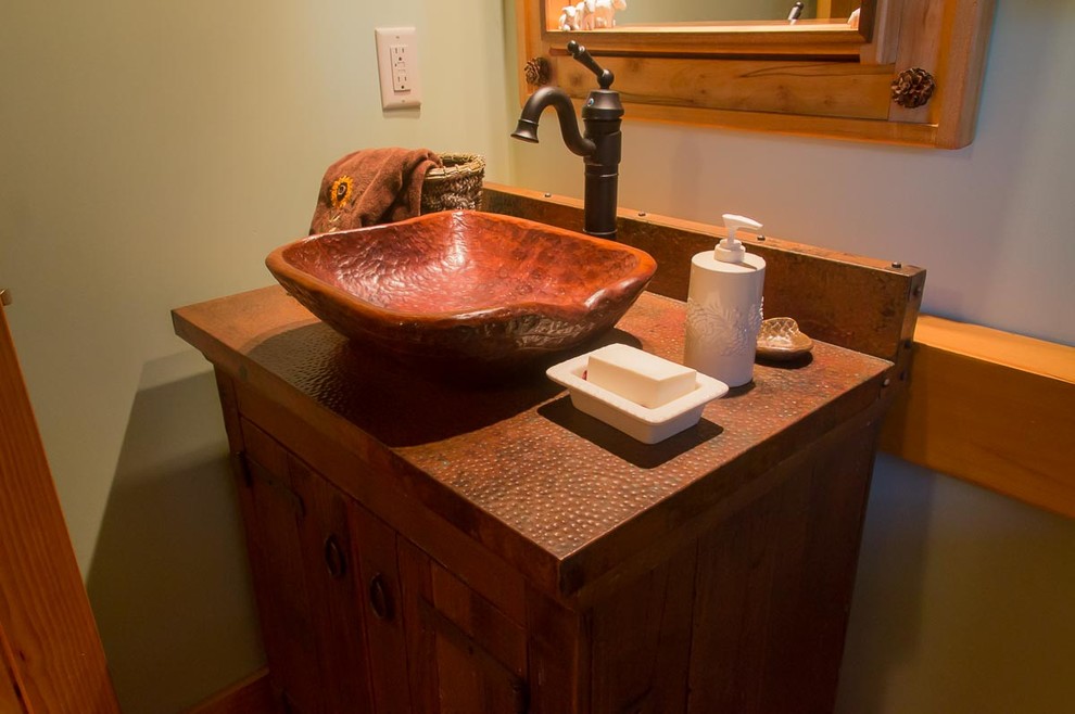Réalisation d'une grande salle d'eau chalet en bois brun avec un placard à porte shaker, un mur vert, une vasque et un plan de toilette en cuivre.