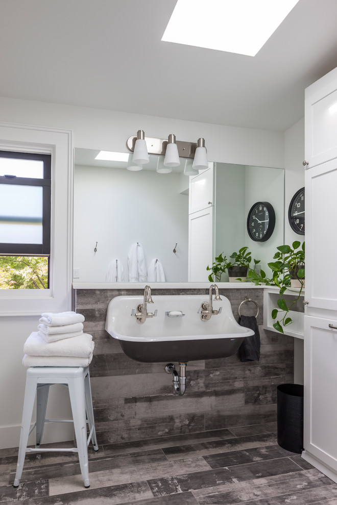 シアトルにある中くらいなトランジショナルスタイルのおしゃれな浴室 (シェーカースタイル扉のキャビネット、白いキャビネット、白い壁、横長型シンク、茶色い床、茶色いタイル、濃色無垢フローリング) の写真
