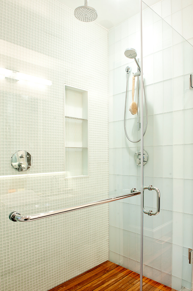 Idee per una stanza da bagno design con doccia alcova, piastrelle bianche, piastrelle di vetro, pavimento in legno massello medio, pavimento marrone e porta doccia a battente