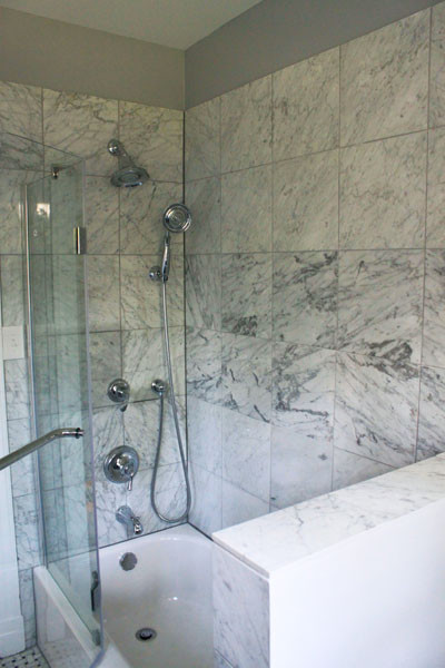 Esempio di una stanza da bagno contemporanea con lavabo a bacinella, ante in legno bruno, top in marmo, vasca/doccia e piastrelle bianche