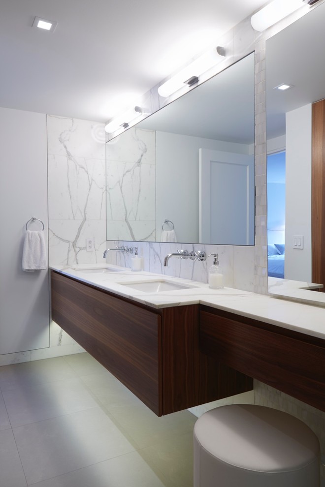 Example of a mid-sized minimalist master stone tile concrete floor and gray floor bathroom design in New York with flat-panel cabinets, dark wood cabinets, a wall-mount toilet, marble countertops, an undermount tub, gray walls and an undermount sink