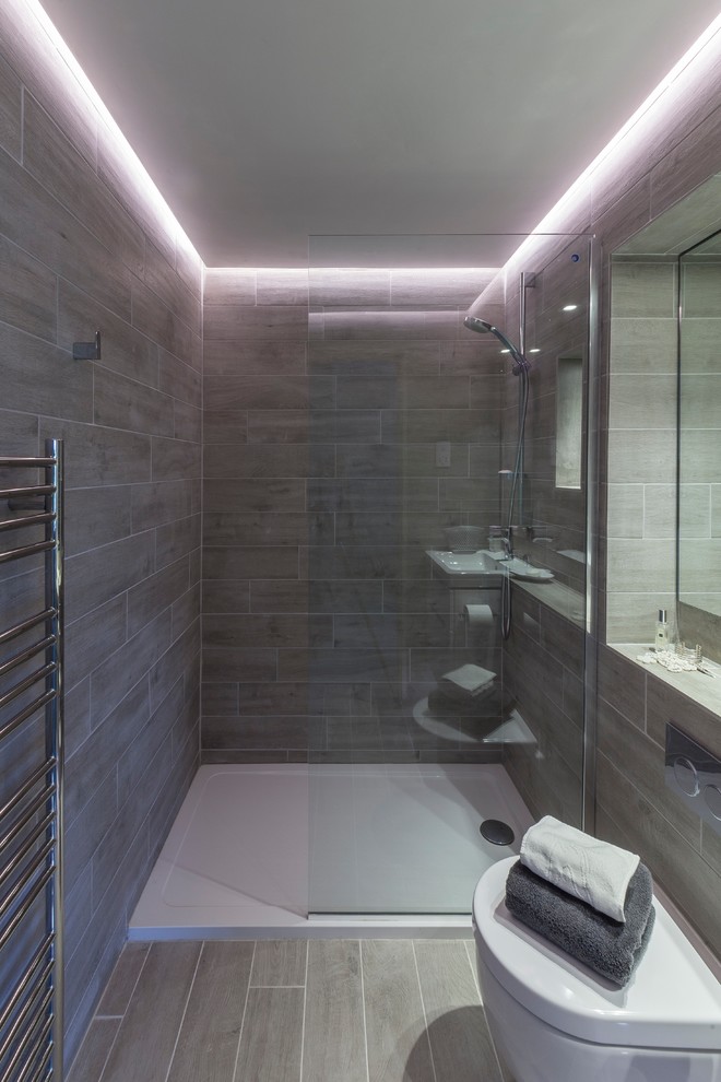 Photo of a small contemporary ensuite bathroom in London with a walk-in shower, a wall mounted toilet, grey tiles, porcelain tiles, grey walls, porcelain flooring, a wall-mounted sink, grey floors and an open shower.