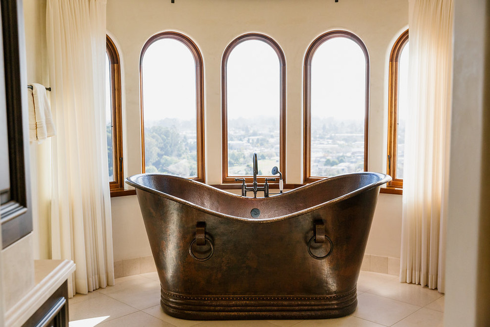 Ispirazione per una stanza da bagno mediterranea con vasca freestanding, pareti beige e pavimento beige