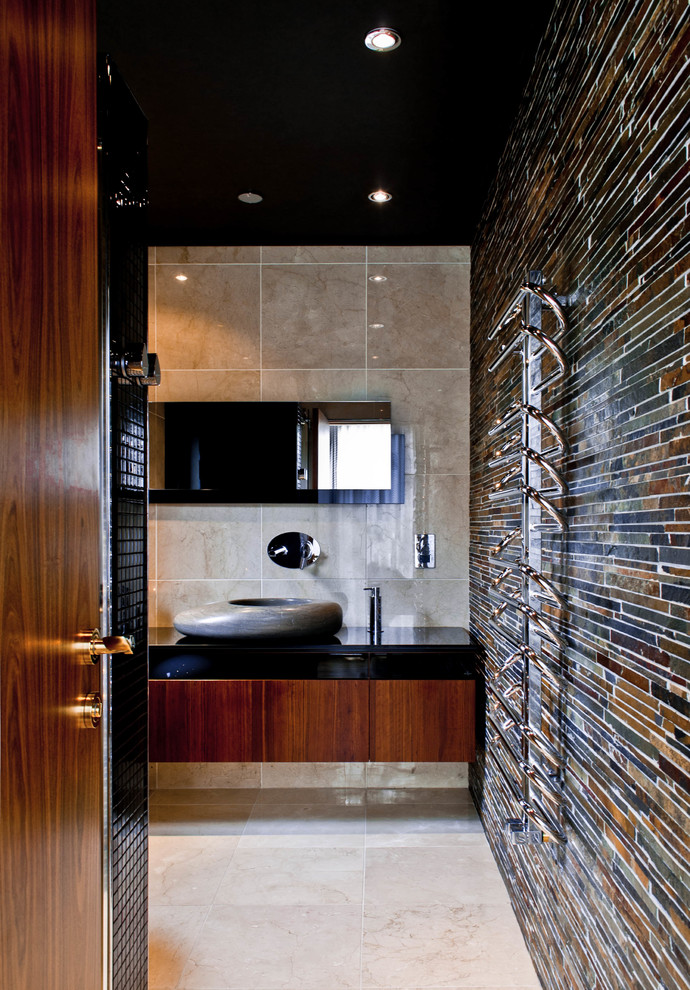 Exempel på ett modernt en-suite badrum, med ett fristående handfat, skåp i mellenmörkt trä, bänkskiva i glas, beige kakel, stenkakel, flerfärgade väggar och marmorgolv