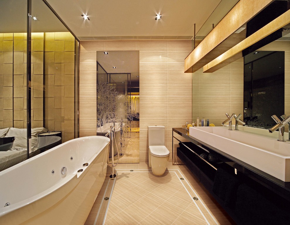 Foto på ett funkis badrum, med ett avlångt handfat, släta luckor, svarta skåp, ett fristående badkar och en toalettstol med hel cisternkåpa