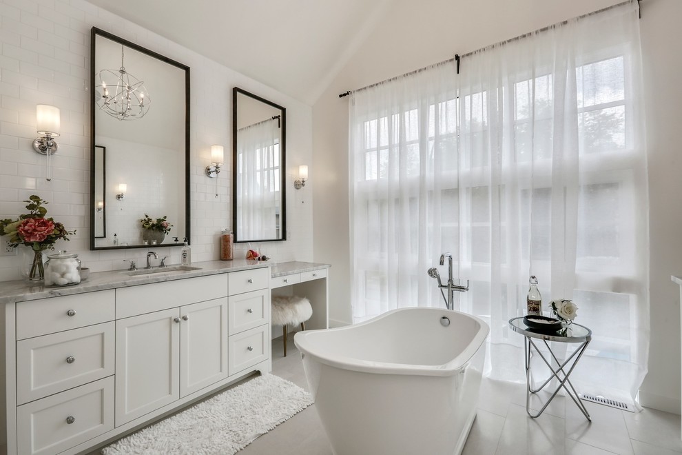 Inspiration for a rural ensuite bathroom in Calgary with shaker cabinets, white cabinets, a freestanding bath, white tiles, metro tiles, white walls, a submerged sink, grey floors and grey worktops.