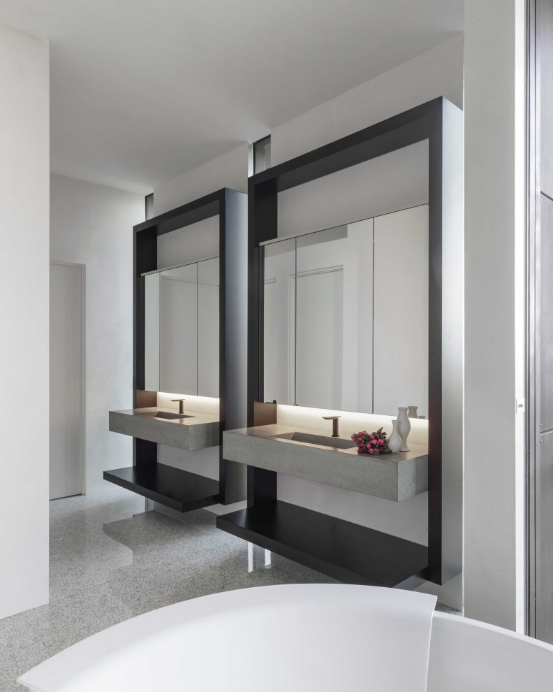 На фото: большая главная ванная комната в стиле неоклассика (современная классика) с серыми фасадами, отдельно стоящей ванной, белыми стенами, врезной раковиной, серым полом, серой столешницей, тумбой под две раковины и подвесной тумбой