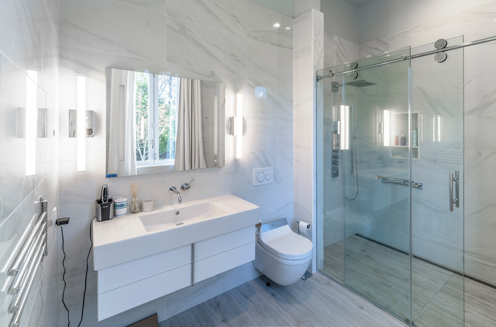 Идея дизайна: маленькая ванная комната в стиле модернизм с плоскими фасадами, белыми фасадами, душем без бортиков, биде, черно-белой плиткой, разноцветной плиткой, удлиненной плиткой, разноцветными стенами, полом из керамогранита, душевой кабиной, монолитной раковиной, столешницей из искусственного камня, серым полом, душем с раздвижными дверями и белой столешницей для на участке и в саду