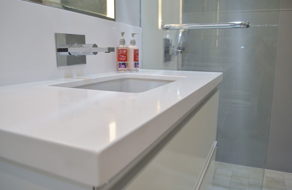 Foto di una piccola stanza da bagno minimalista con lavabo sottopiano, ante bianche, top in quarzo composito e doccia aperta