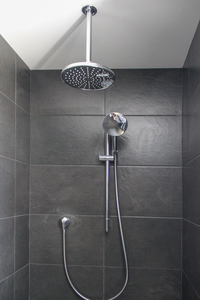 Idee per una stanza da bagno con doccia minimalista di medie dimensioni con ante lisce, ante bianche, doccia aperta, piastrelle nere, piastrelle in ceramica, pareti grigie, pavimento in cementine, lavabo integrato, top in vetro, pavimento nero e doccia aperta