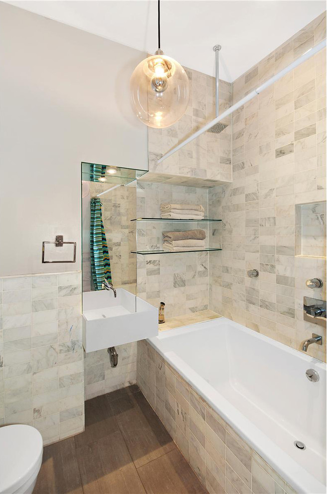 Drop-in bathtub - mid-sized modern gray tile and subway tile porcelain tile and brown floor drop-in bathtub idea in New York with a one-piece toilet, gray walls and a wall-mount sink