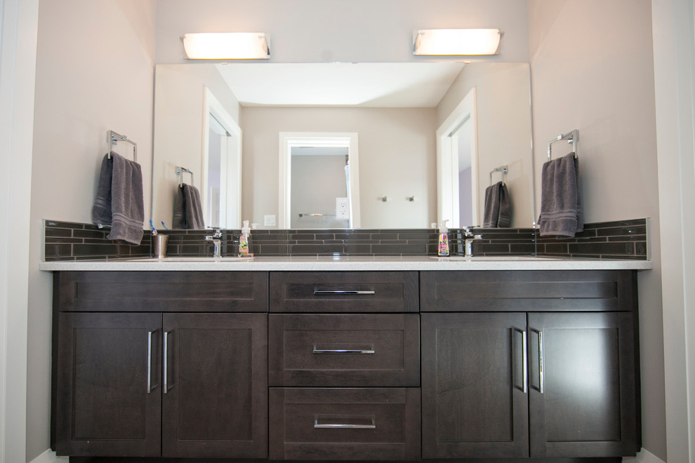 This is an example of a medium sized contemporary family bathroom in Edmonton with recessed-panel cabinets, dark wood cabinets, laminate worktops, a one-piece toilet, black tiles, glass tiles, grey walls, ceramic flooring and a built-in sink.