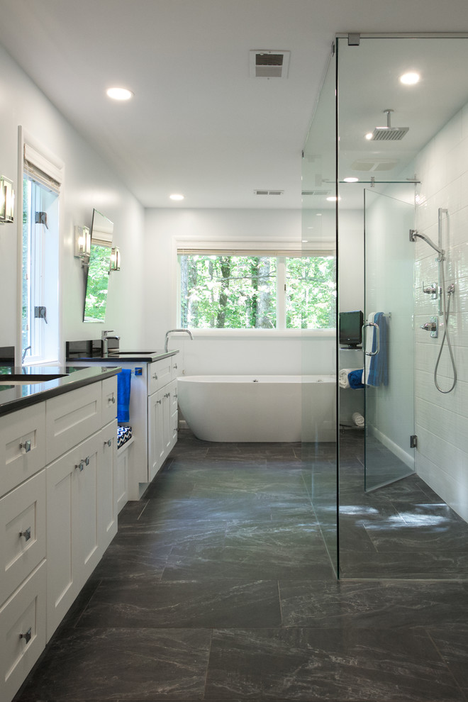 Large contemporary ensuite bathroom in Atlanta with recessed-panel cabinets, white cabinets, a freestanding bath, a built-in shower, white tiles, ceramic tiles, white walls, slate flooring, a submerged sink, marble worktops, grey floors, a hinged door and black worktops.