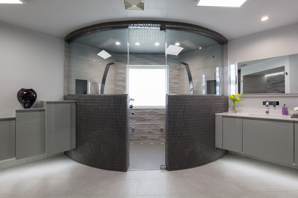 Exemple d'une salle de bain principale tendance de taille moyenne avec un placard à porte plane, des portes de placard grises, un plan de toilette en surface solide, un carrelage gris, un carrelage noir, un sol en carrelage de porcelaine, une baignoire posée, une douche double, WC séparés, mosaïque, un mur gris et un lavabo intégré.