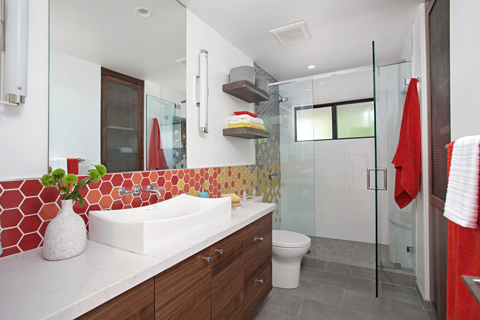 Пример оригинального дизайна: ванная комната в современном стиле с плоскими фасадами, фасадами цвета дерева среднего тона, душем в нише, серой плиткой, оранжевой плиткой, красной плиткой, белой плиткой, желтой плиткой, белыми стенами, душевой кабиной, настольной раковиной, серым полом и душем с распашными дверями