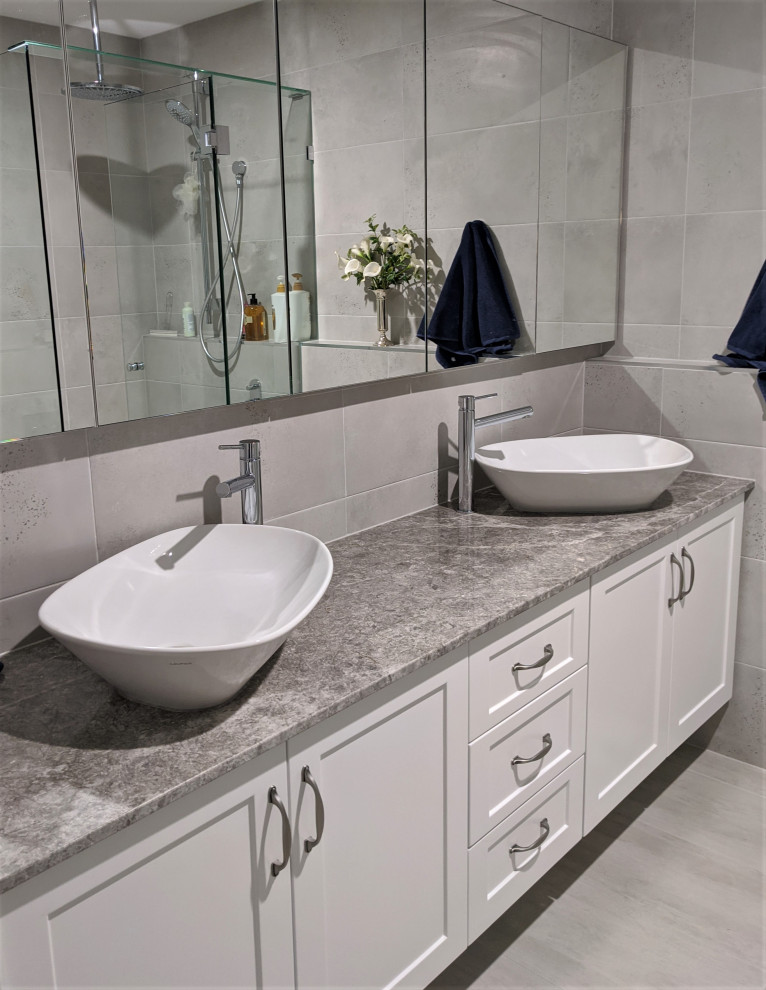 Bild på ett funkis badrum, med skåp i shakerstil, vita skåp, en hörndusch, grå kakel, keramikplattor, ett fristående handfat och marmorbänkskiva