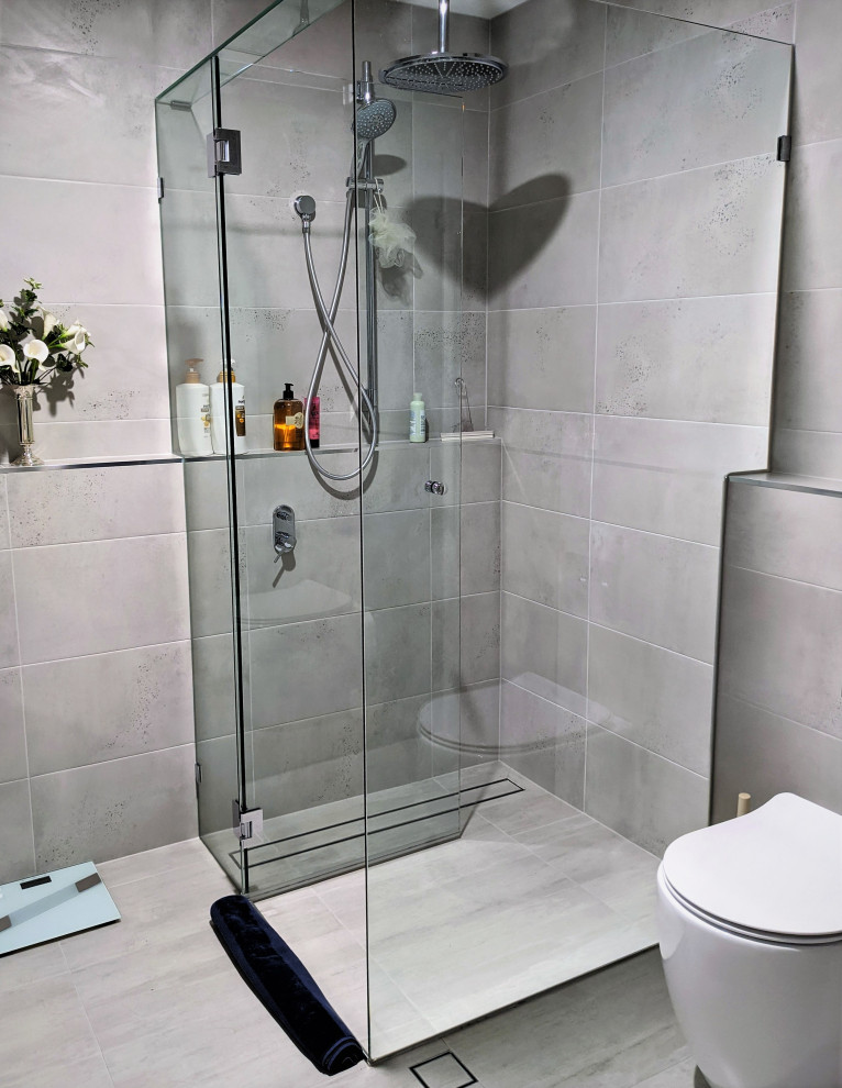 Idee per una stanza da bagno moderna con ante in stile shaker, ante bianche, doccia ad angolo, WC monopezzo, piastrelle grigie, piastrelle in ceramica, pavimento con piastrelle in ceramica, top in marmo, pavimento grigio, due lavabi e mobile bagno sospeso