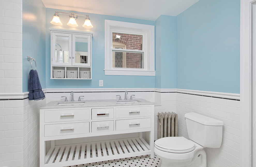 Shabby-Style Duschbad mit weißen Schränken, weißen Fliesen, blauer Wandfarbe, integriertem Waschbecken, flächenbündigen Schrankfronten, Toilette mit Aufsatzspülkasten und Mosaik-Bodenfliesen in Philadelphia