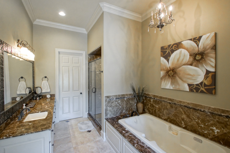Inspiration for a large traditional ensuite bathroom in New Orleans with a submerged sink, raised-panel cabinets, white cabinets, a built-in bath, beige walls and ceramic flooring.