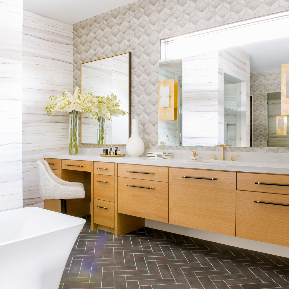 Modernes Badezimmer mit flächenbündigen Schrankfronten, hellbraunen Holzschränken, freistehender Badewanne, grauer Wandfarbe, Unterbauwaschbecken, grauem Boden und weißer Waschtischplatte in Dallas
