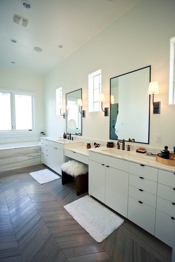 Foto de cuarto de baño principal moderno grande con lavabo encastrado, armarios con paneles lisos, puertas de armario blancas, encimera de mármol, bañera esquinera, paredes blancas y suelo de madera oscura