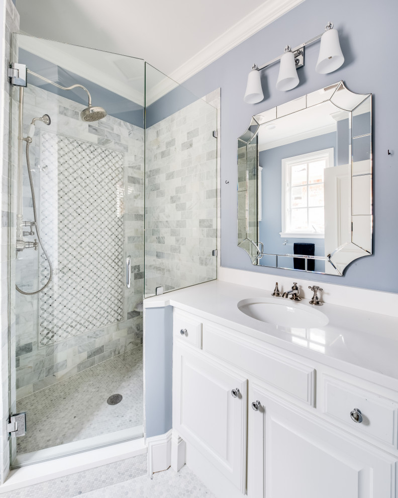 На фото: ванная комната в стиле неоклассика (современная классика) с фасадами с выступающей филенкой, белыми фасадами, угловым душем, серой плиткой, синими стенами, врезной раковиной, душем с распашными дверями, белой столешницей, тумбой под одну раковину, встроенной тумбой, плиткой кабанчик и серым полом