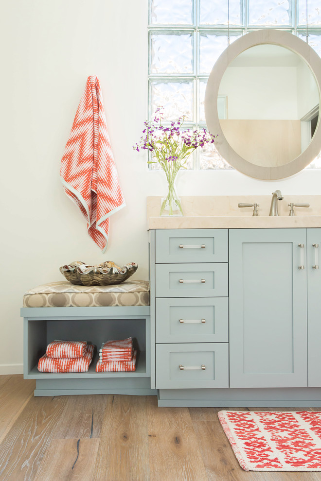 Ejemplo de cuarto de baño infantil costero grande con armarios estilo shaker, puertas de armario azules, ducha empotrada, sanitario de una pieza, baldosas y/o azulejos beige, baldosas y/o azulejos de mármol, paredes blancas, suelo de madera clara, lavabo bajoencimera, encimera de mármol, suelo gris y ducha con puerta con bisagras